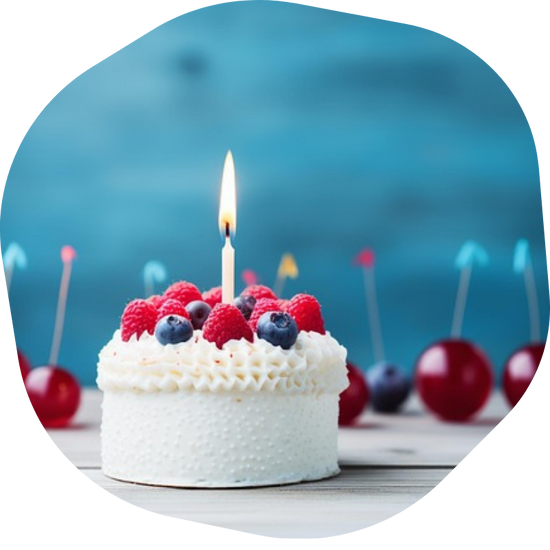 white celebration cake with berries and single candle